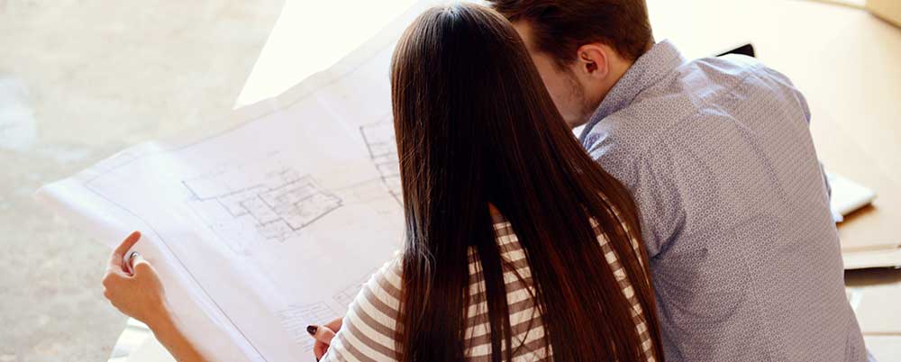 young couple looking at blueprint